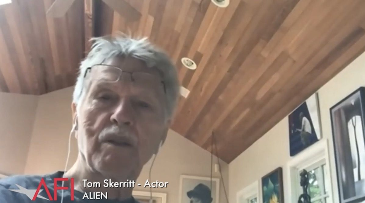 Uomo anziano con capelli grigi e occhiali parla in videochiamata, didascalia «Tom Skerritt – Actor, ALIEN», soffitto in legno sullo sfondo